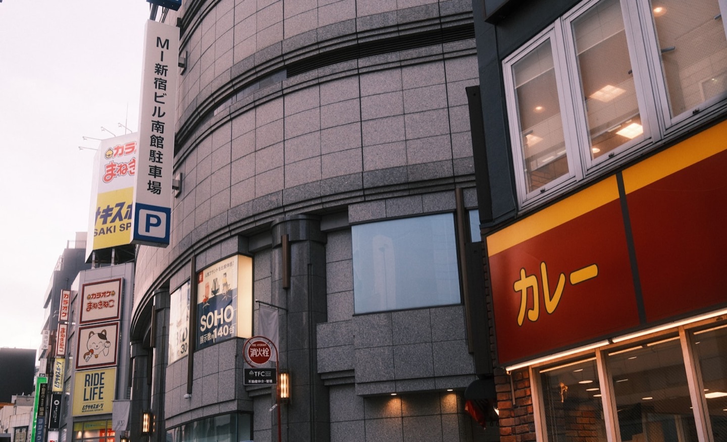 A Japanese city street corner stacked with Japanese-language shop and building signs