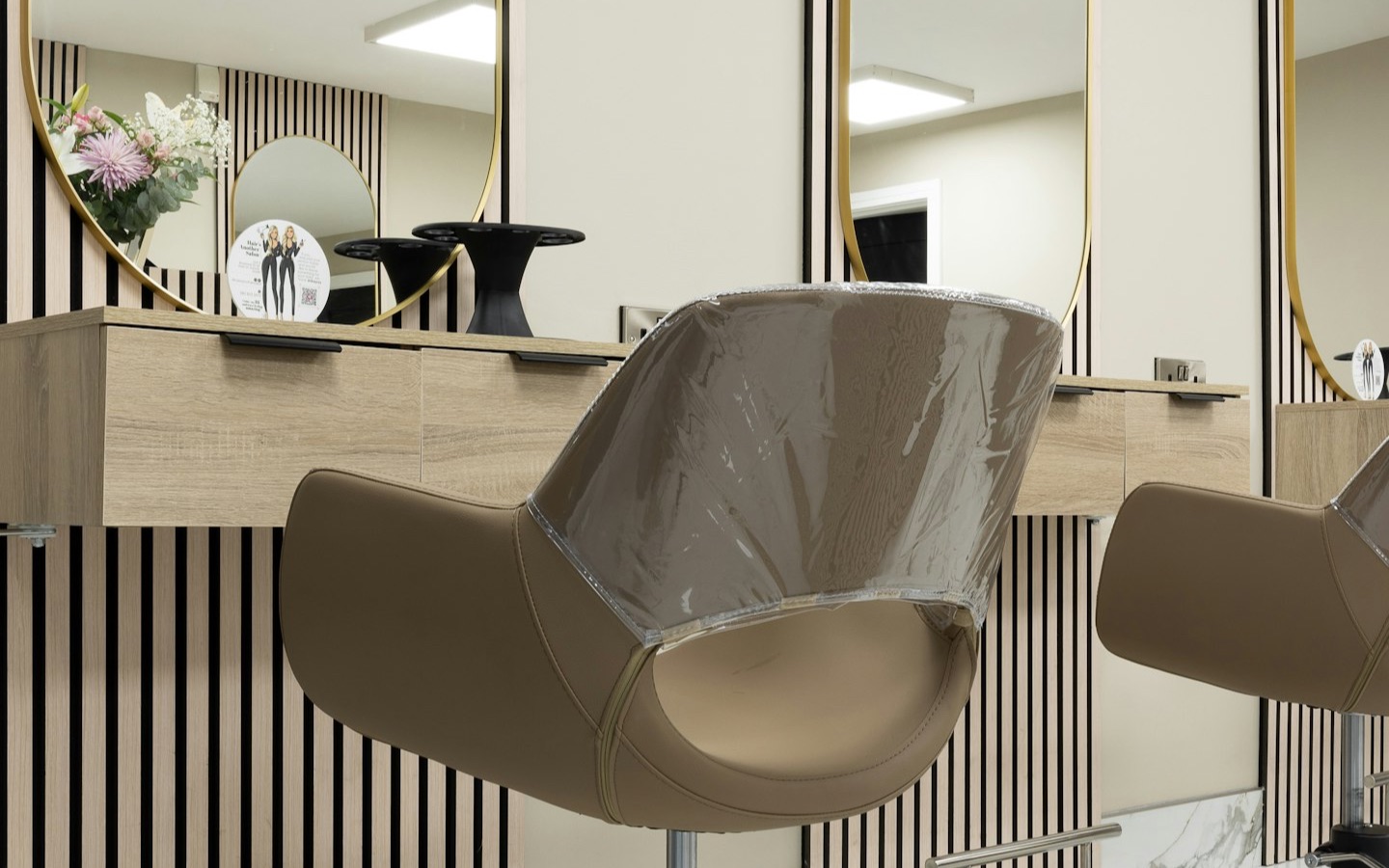 The interior of a modern hair salon with styling chairs, arched mirrors and a marble floor