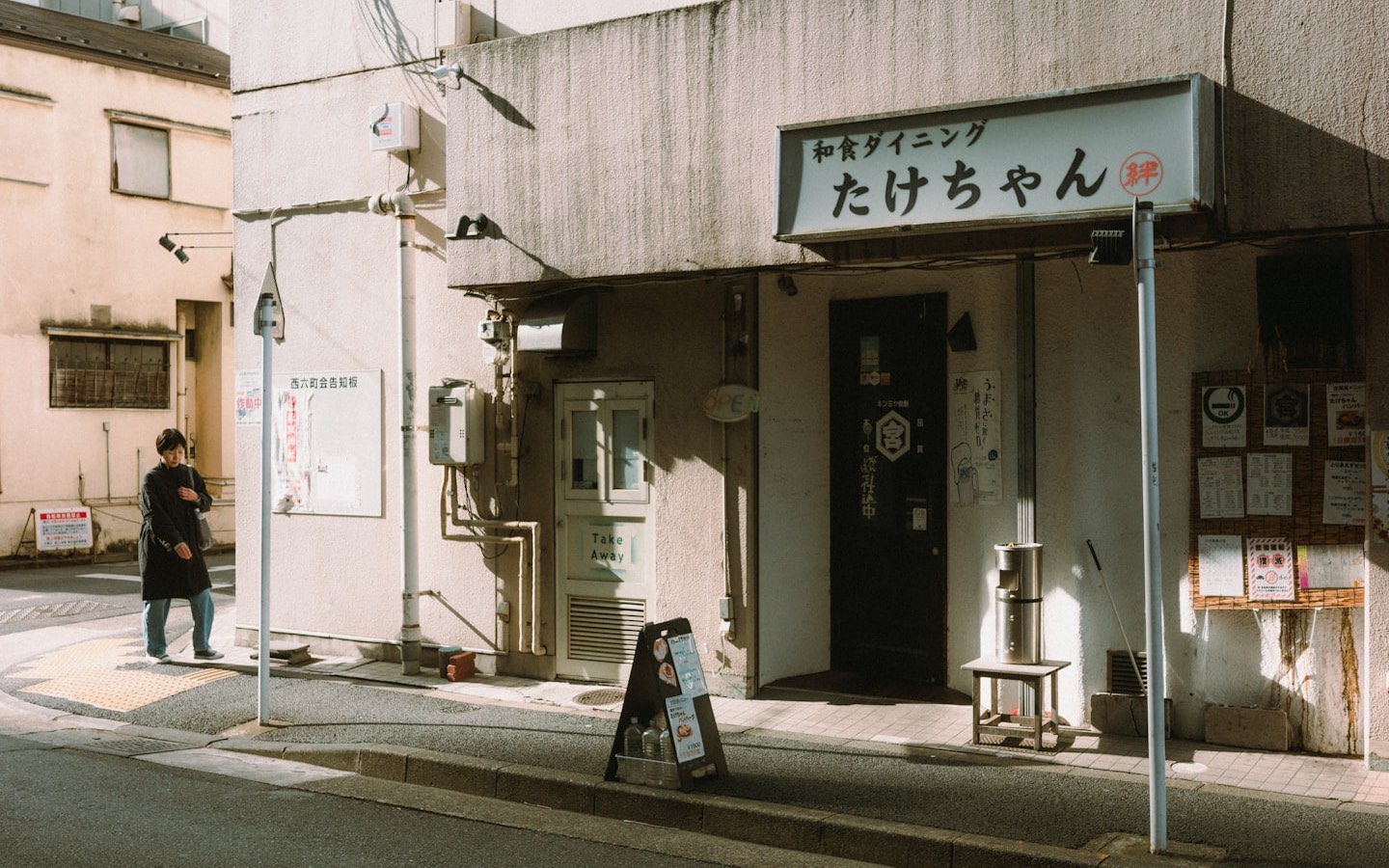 A person standing outside a small Japanese restaurant entrance in Tokyo