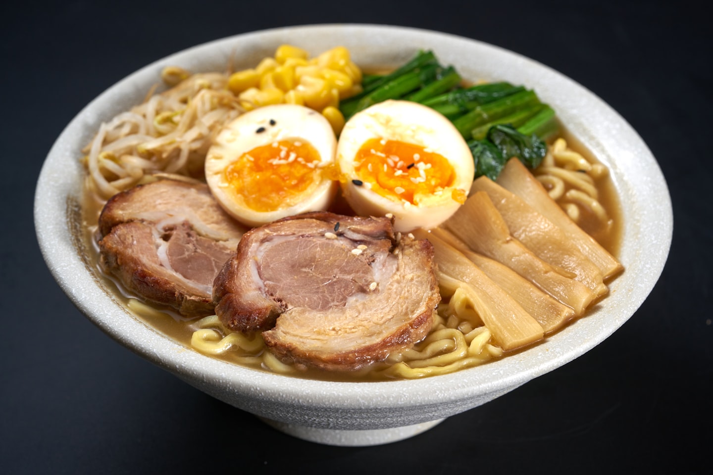 A bowl of shoyu ramen with chashu pork, a soft-boiled egg, bamboo shoots and greens
