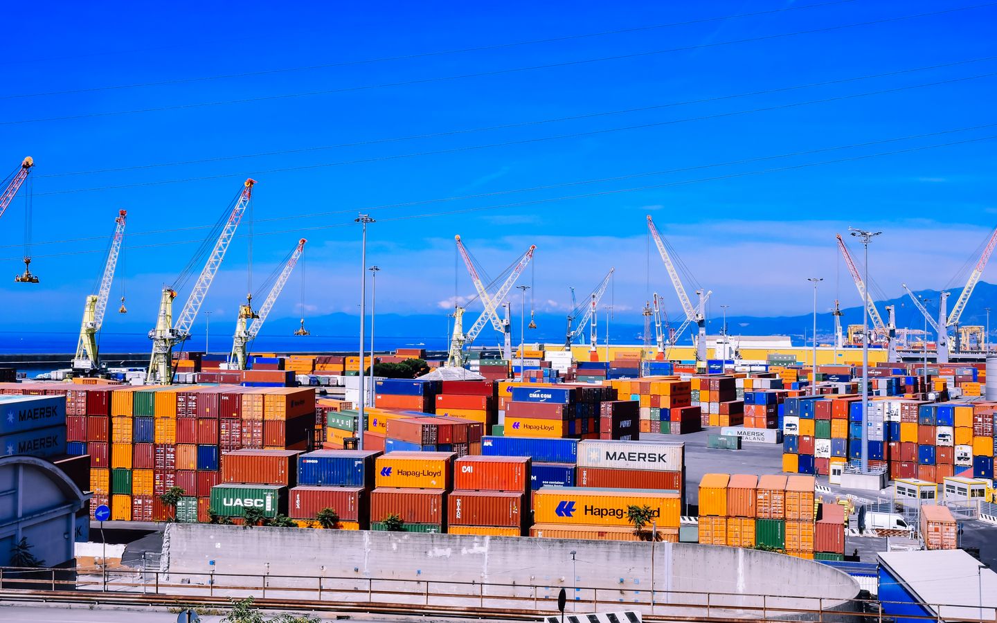 A busy container port stacked with colourful shipping containers and cranes